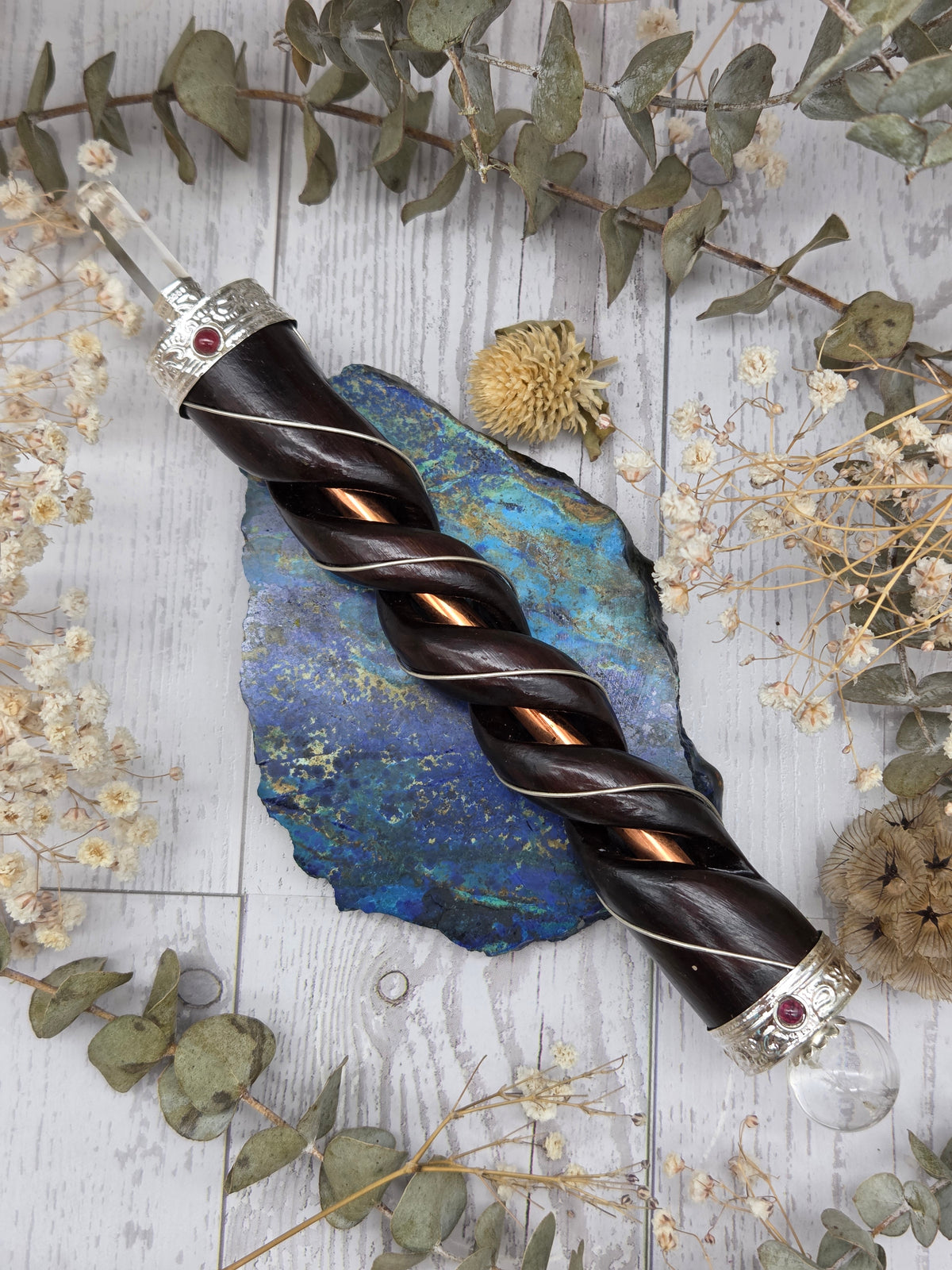 Clear quartz wand with rosewood and copper on a decorative background