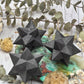 Polished black Shungite Merkaba crystal on a decorative background