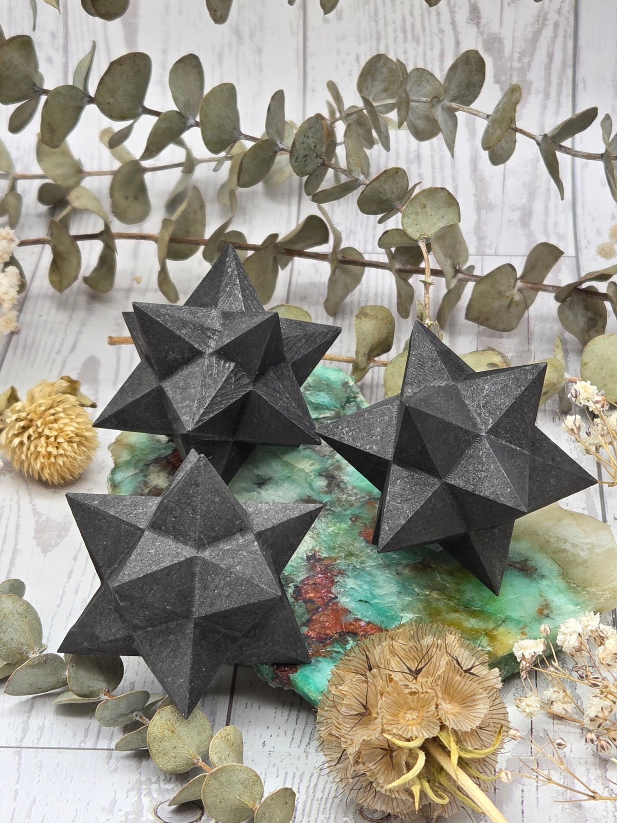 Polished black Shungite Merkaba crystal on a decorative background