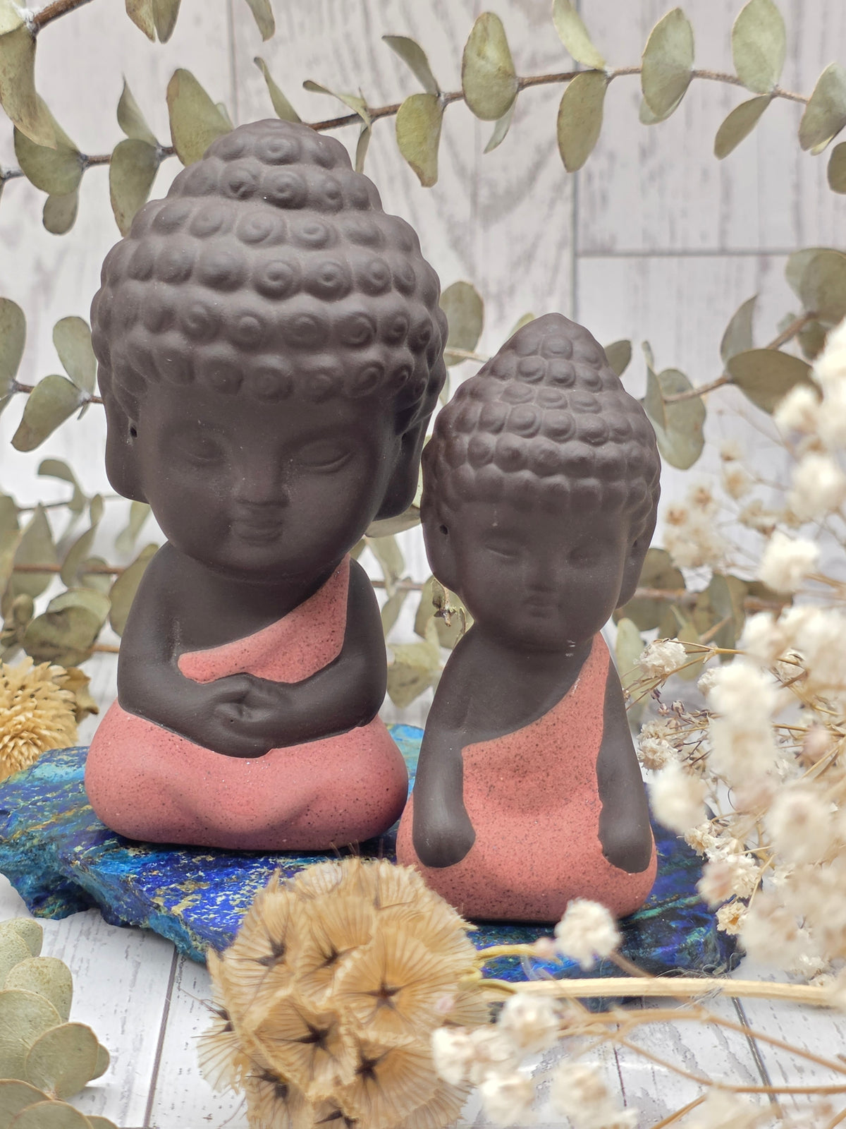 Two Buddha figurines with brown and pink colors