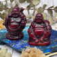 Dark red resin Buddha figurine on a blue stone with foliage