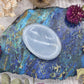 Light blue Angelite worry stone on a colorful background