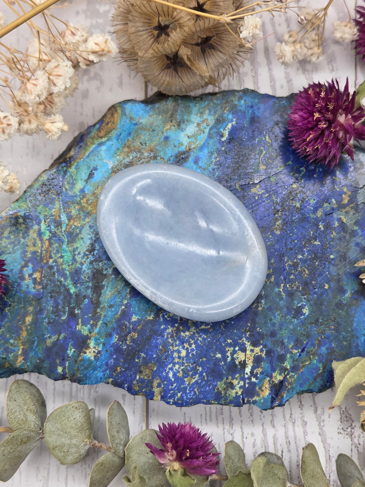 Light blue Angelite worry stone on a colorful background