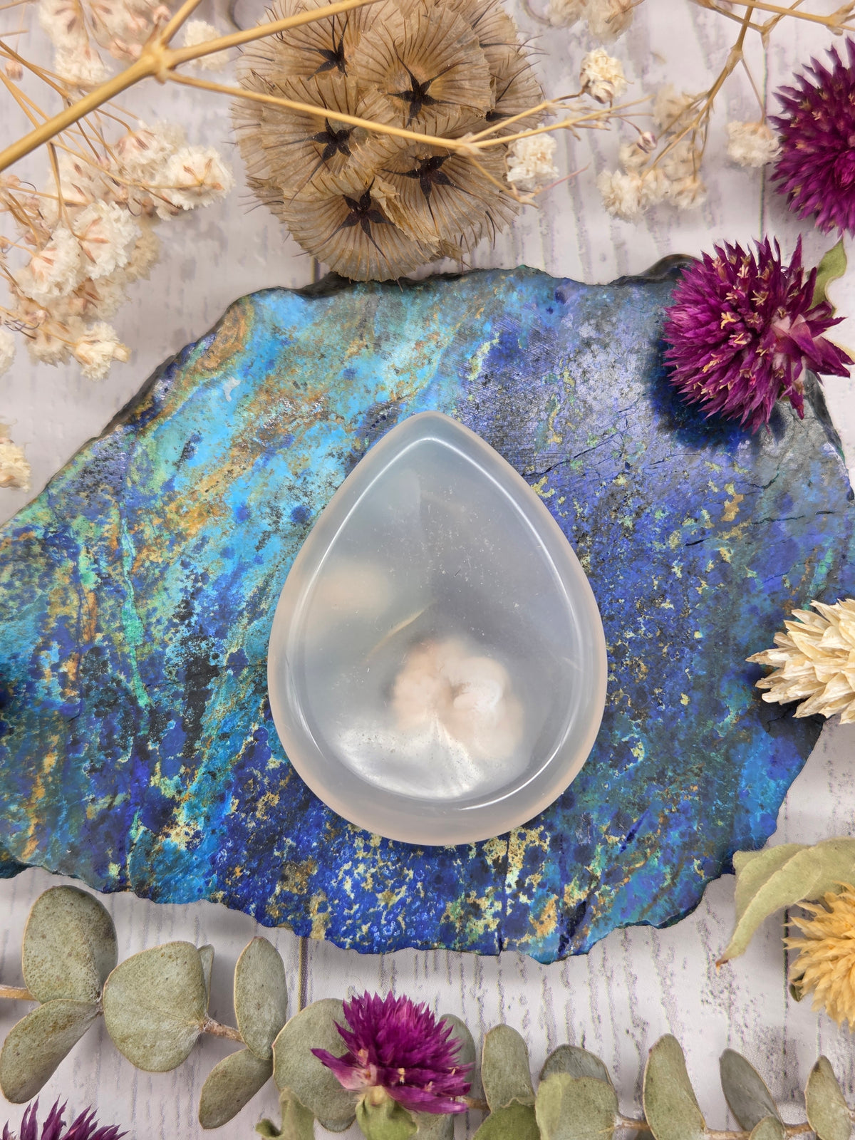 Flower Agate teardrop worry stone on a colorful background
