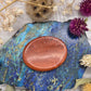 Polished Red Jasper worry stone on a colorful background with dried flowers