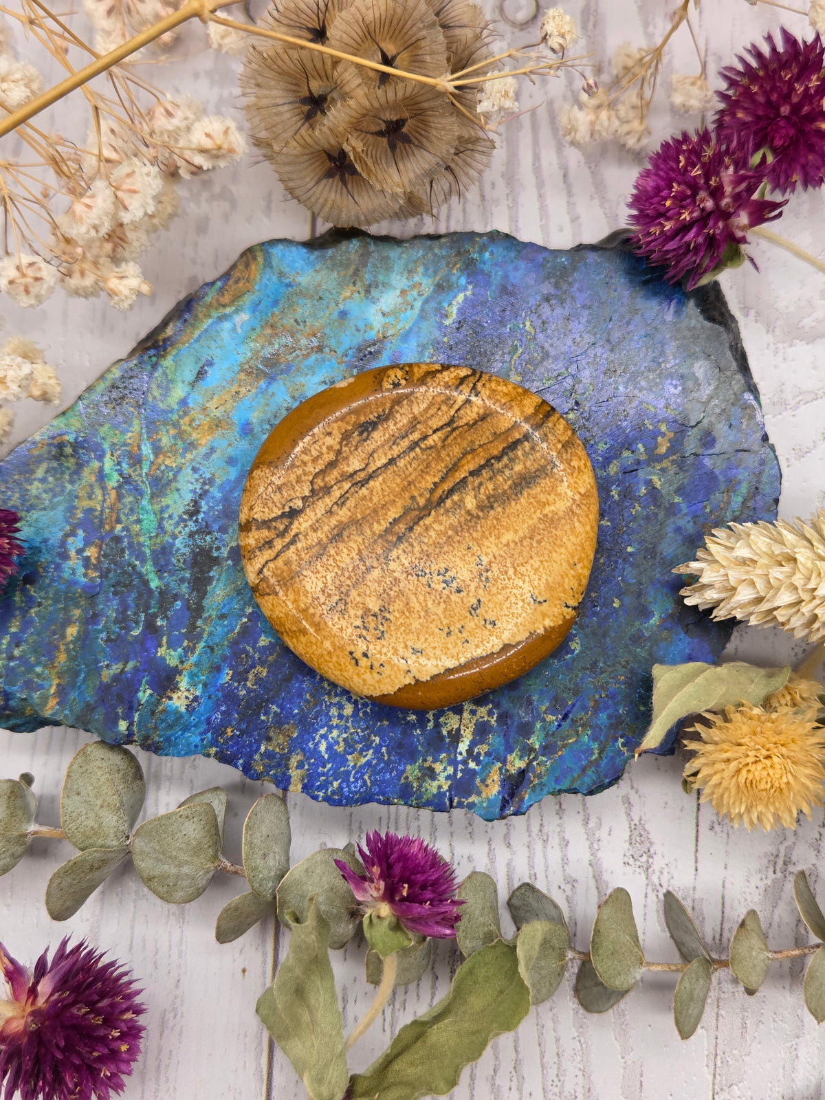 Picture Jasper worry stone on a colorful background with dried flowers