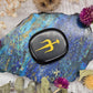 Obsidian etched pocket stone on a colorful background
