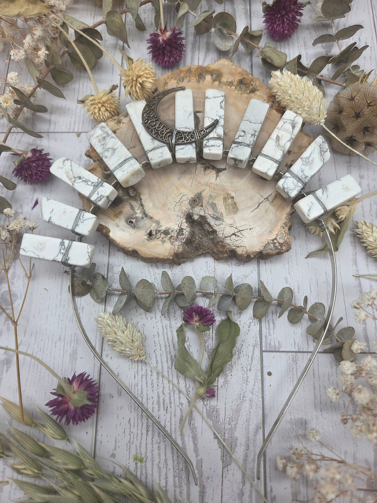 Howlite crow carving surrounded by dried flowers
