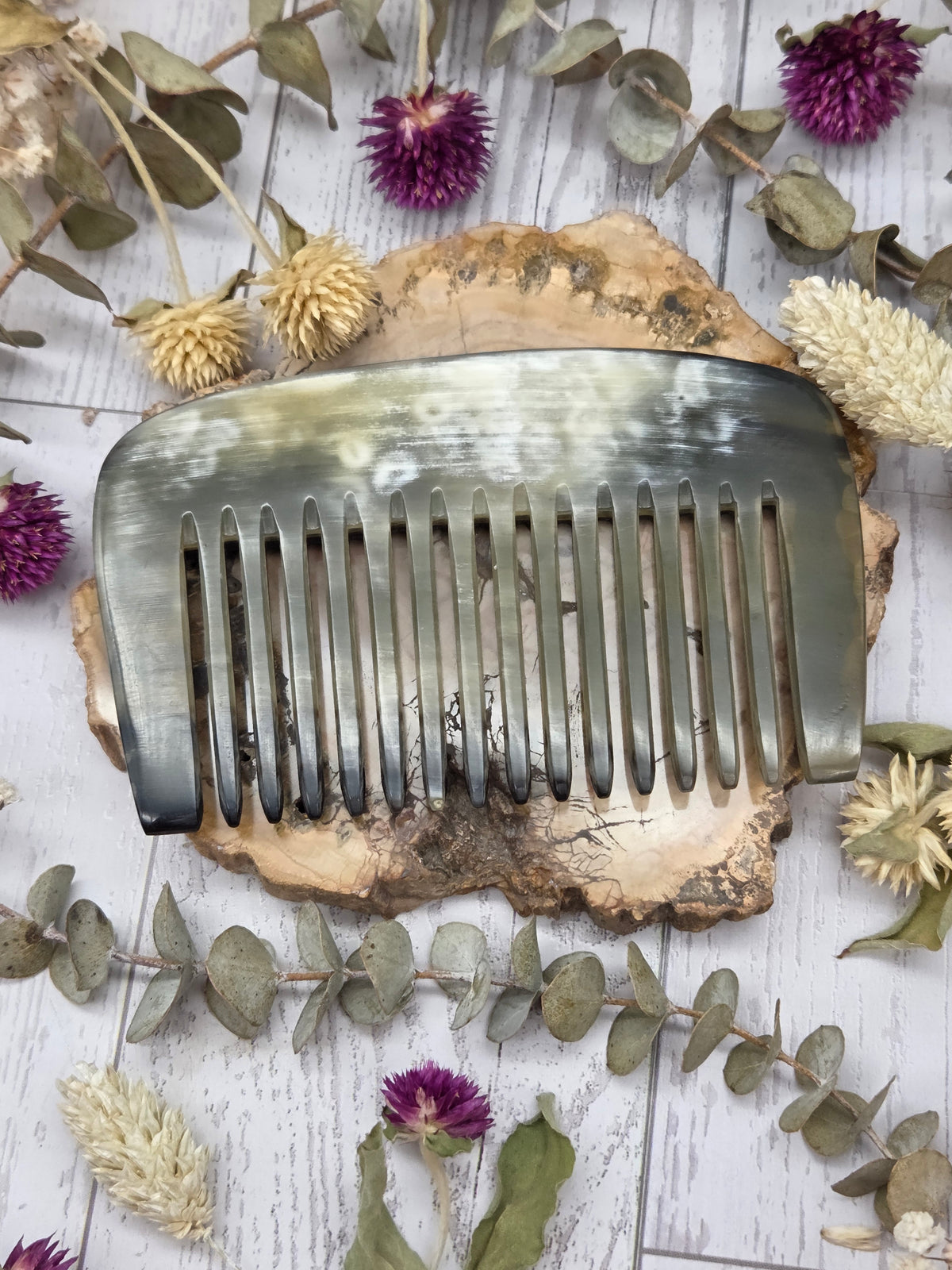 Water buffalo horn comb with polished surface on a wooden background