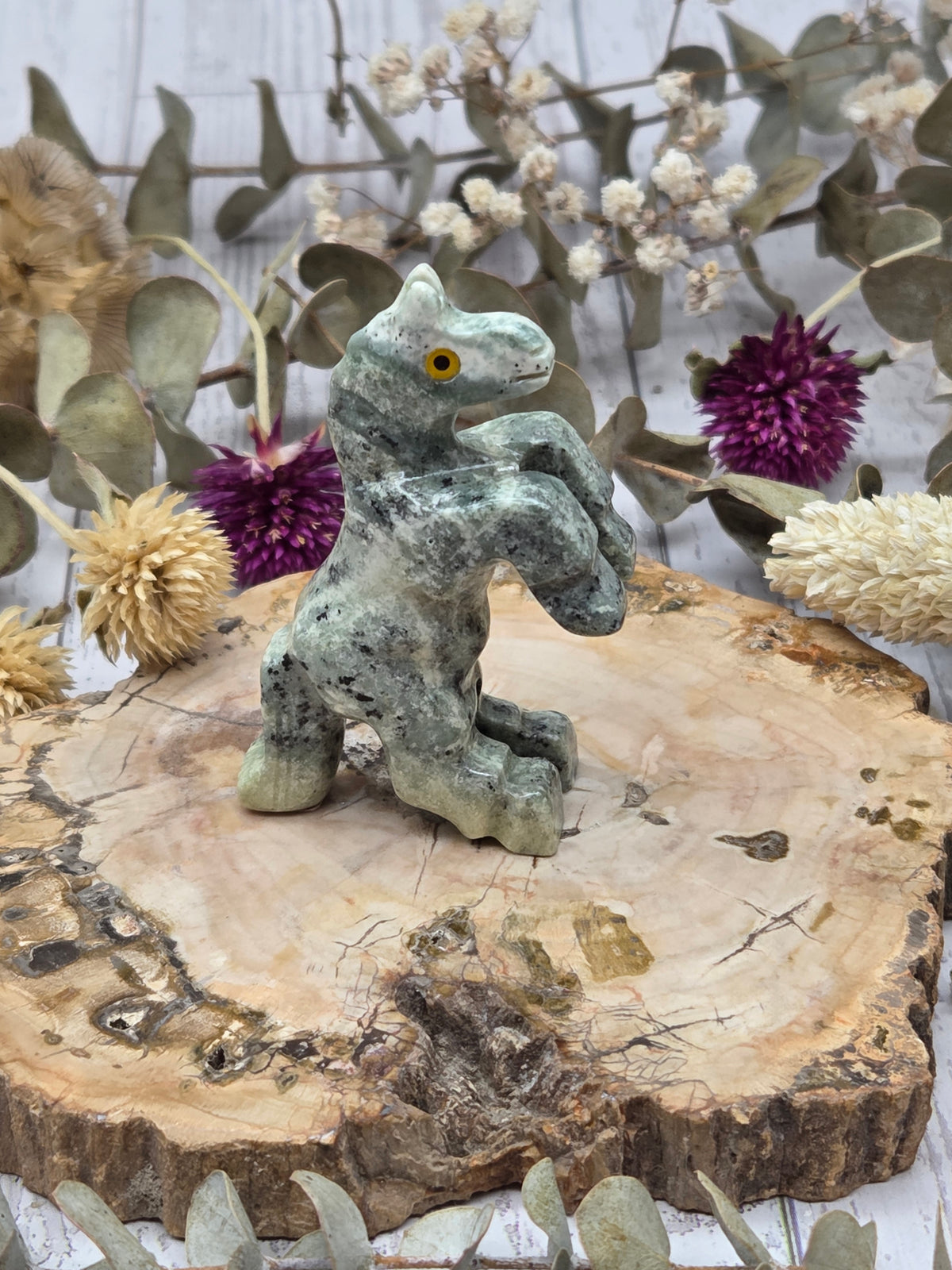 Serpentine rearing horse figurine on a wooden base with floral background