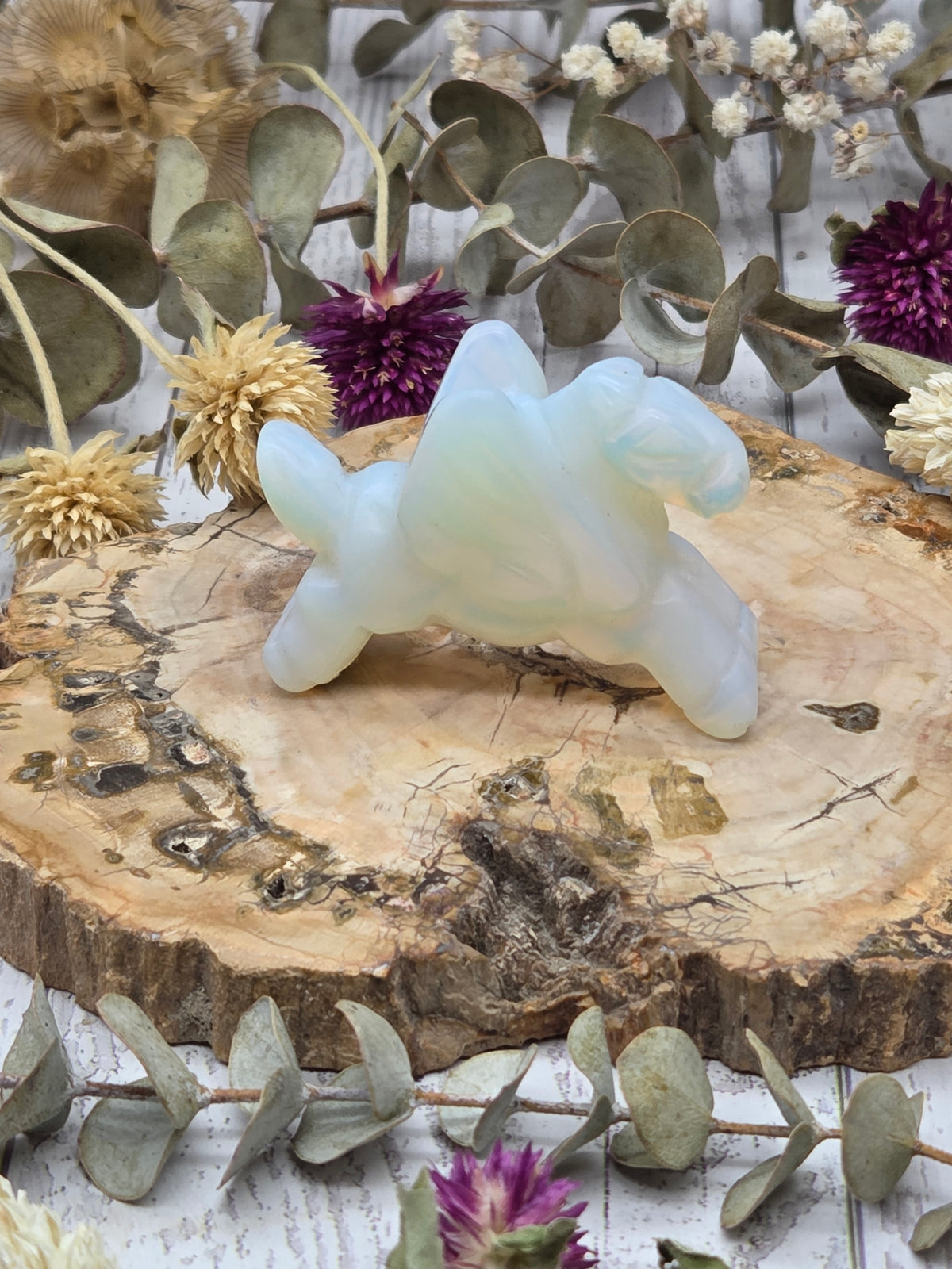 Opalite Pegasus figurine on a wooden base surrounded by dried flowers