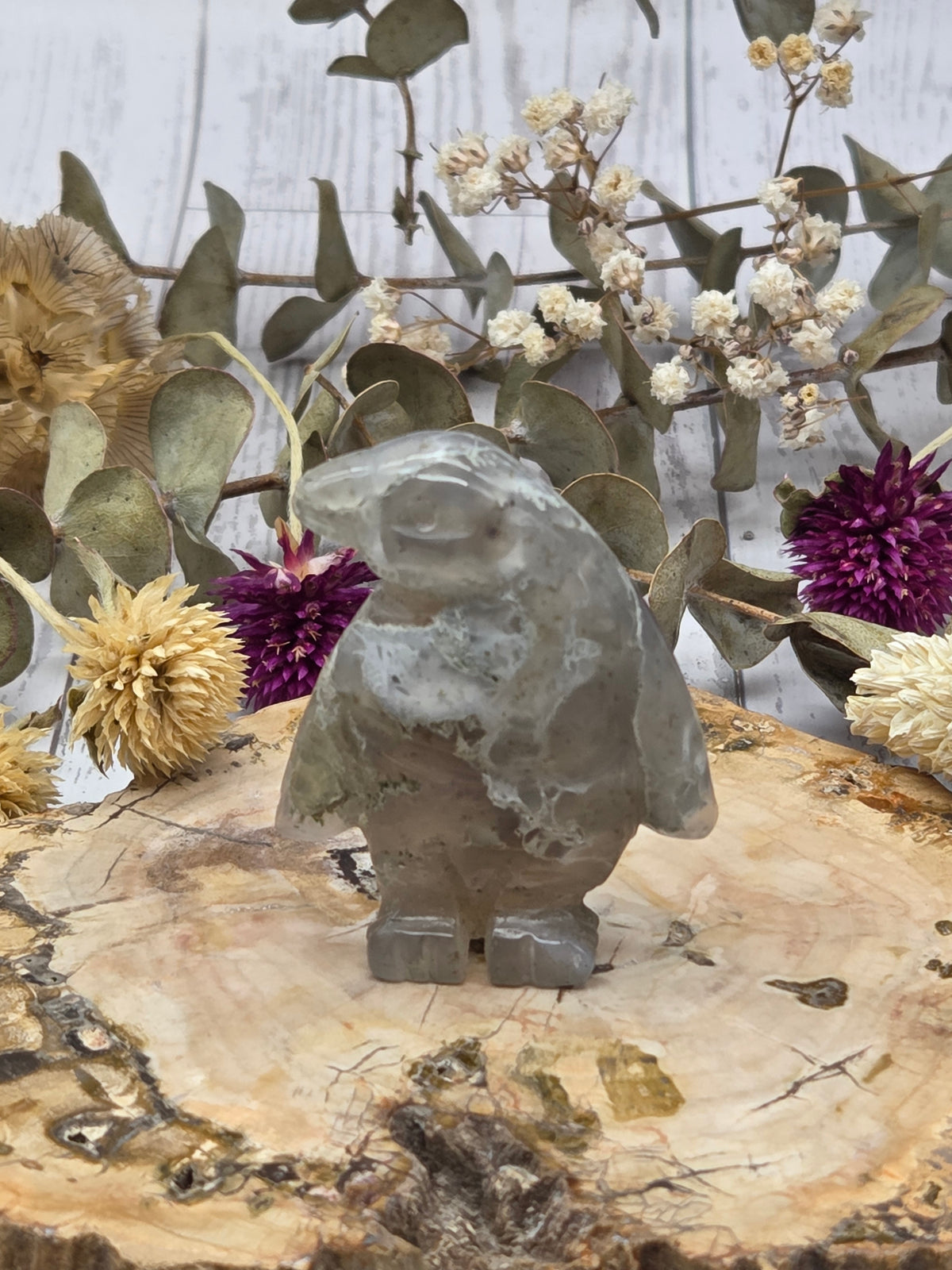 Moss agate penguin figurine with green and gray hues on a wooden base