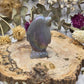 Iridescent aura agate penguin figurine on a wooden base with dried flowers