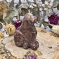 Strawberry Onyx dog carving on a wooden base surrounded by dried flowers