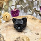 Obsidian cat head carving with third eye on a wooden surface