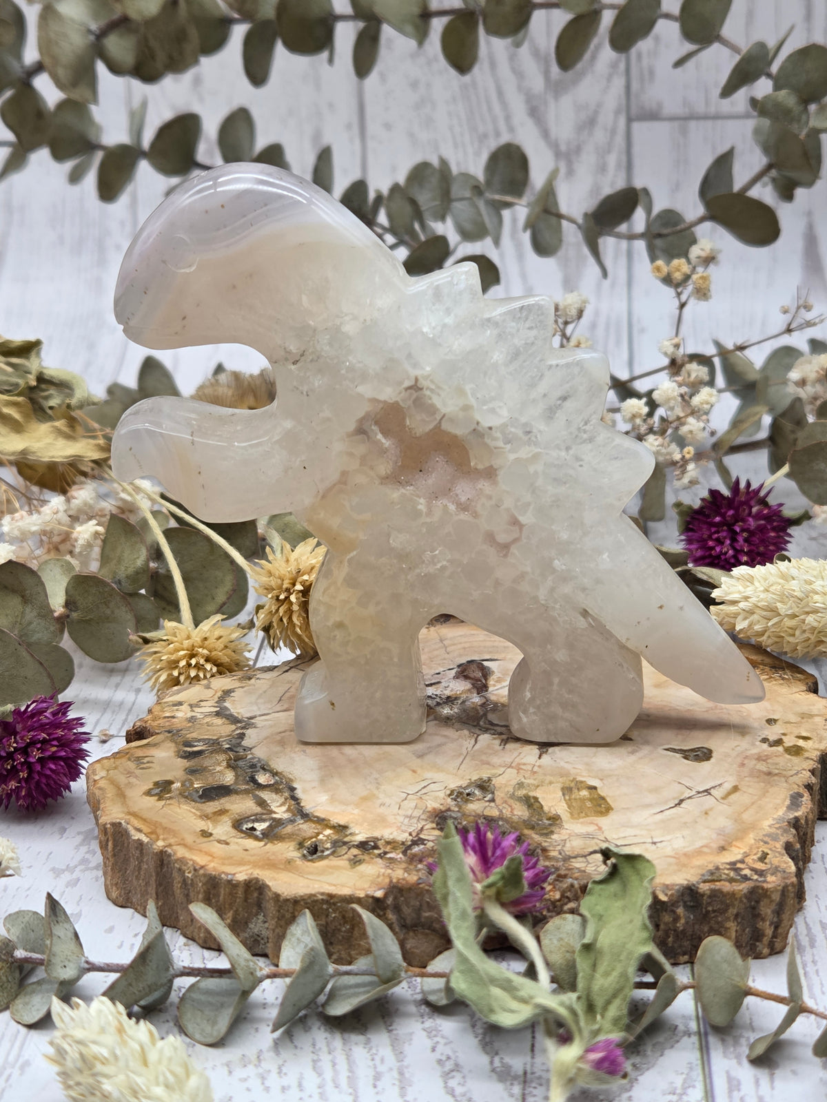 Agate dinosaur figurine on a wooden base with floral background