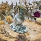 Moss agate kangaroo carving on a wooden base surrounded by dried flowers