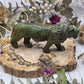 Serpentine lion carving on a wooden base with floral background