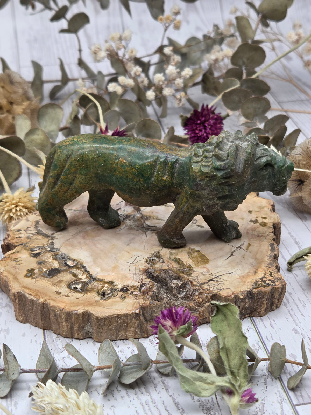 Serpentine lion carving on a wooden base with floral background