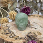 Green fluorite skull on a wooden slab with dried flowers