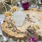 Clear quartz skull on a wooden base surrounded by dried flowers