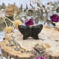Golden sheen obsidian butterfly carving on a wooden slab with dried flowers