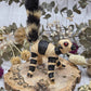 Banana fiber ringtail lemur figurine with beige and black colors on a wooden base