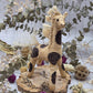 Banana fiber giraffe figurine on a wooden base with dried flowers