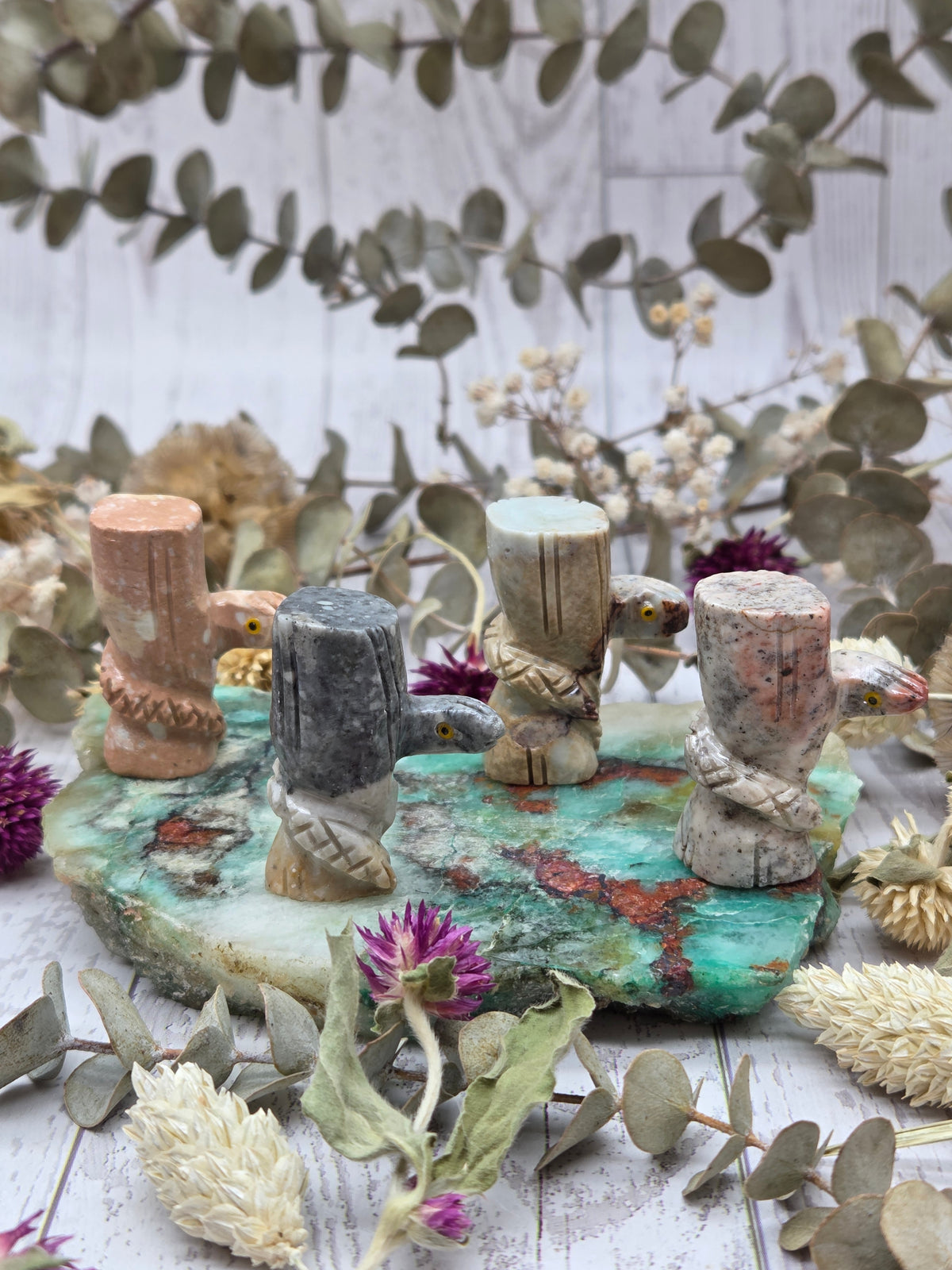 A collection of soapstone snake carvings in various colors