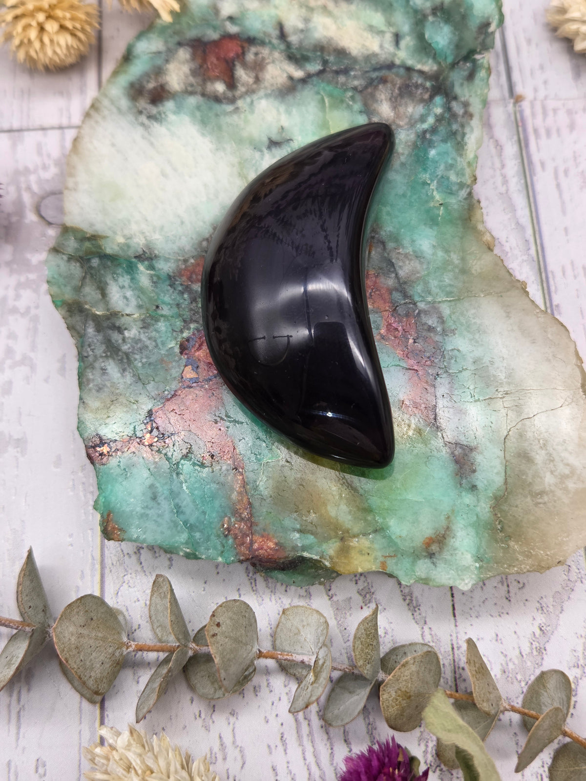 Rainbow Obsidian moon carving on a colorful stone background