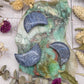 Blue Dumortierite moon carving on a colorful background with dried flowers