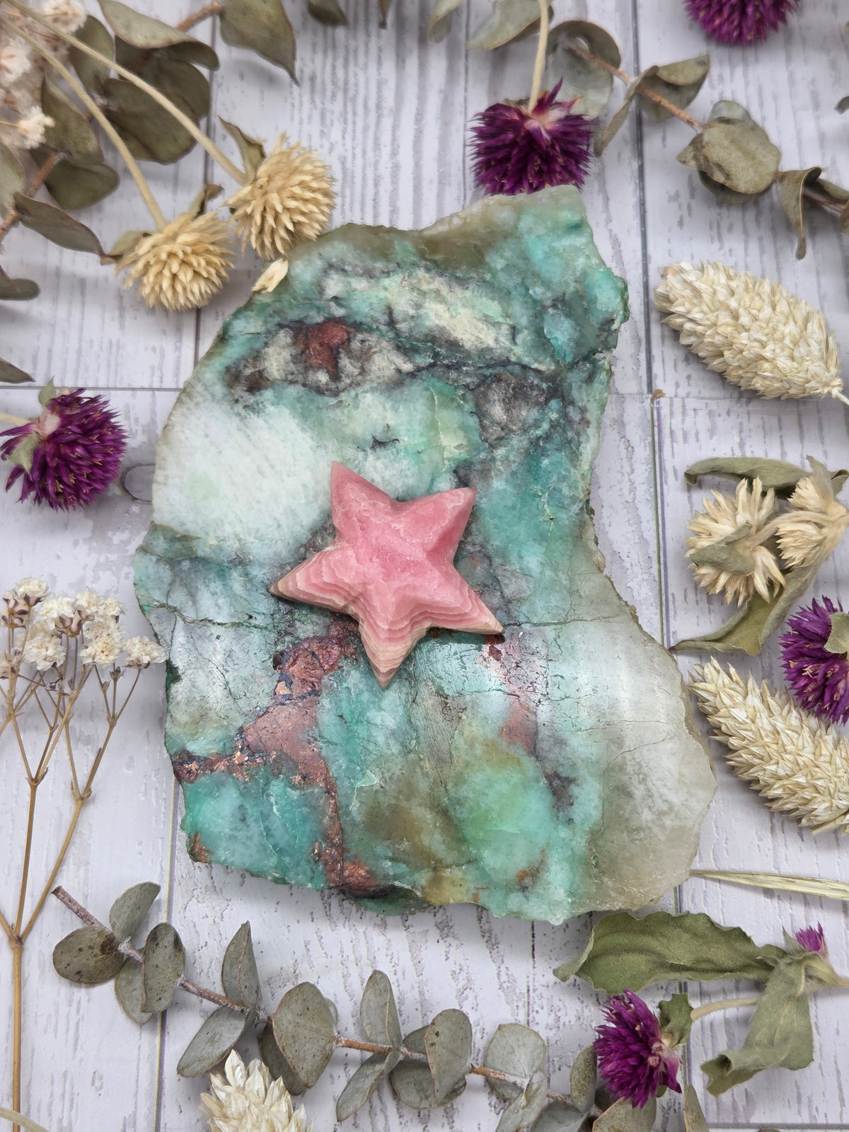 Pink rhodochrosite star carving on a green stone background