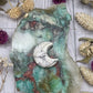 A small polished howlite moon carving on a colorful stone background