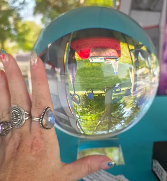 A hand beside the large clear crystal sphere to show its scale